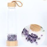 Glass and bamboo water bottle with amethyst crystals.
